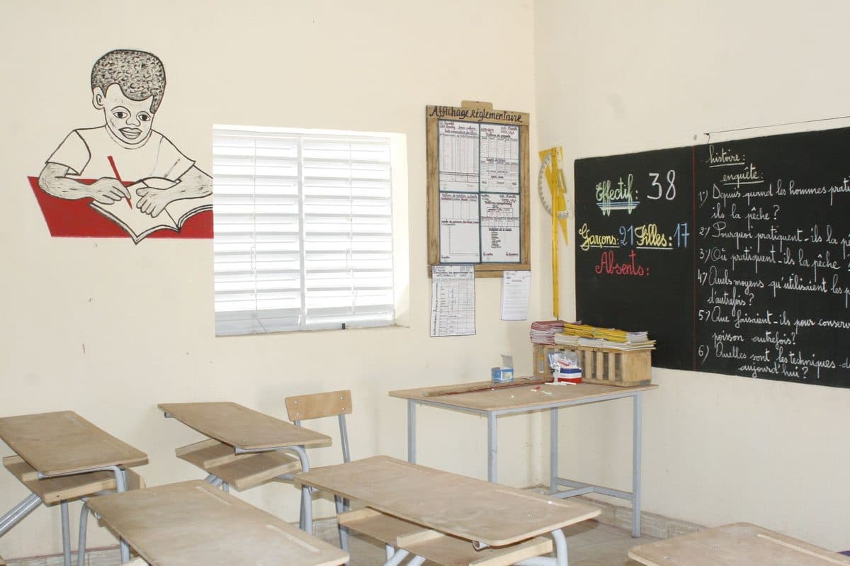 An empty classroom with rows of wooden desks and a chalkboard at the front