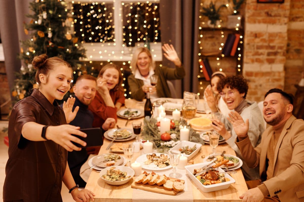 Friends laughing around a long dinner table set for a holiday meal