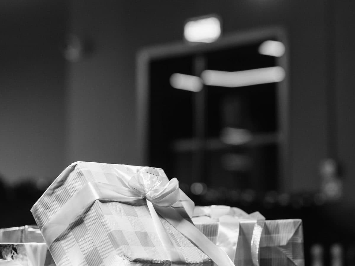 Black-and-white close-up of wrapped gift boxes with ribbon, piled up in a room